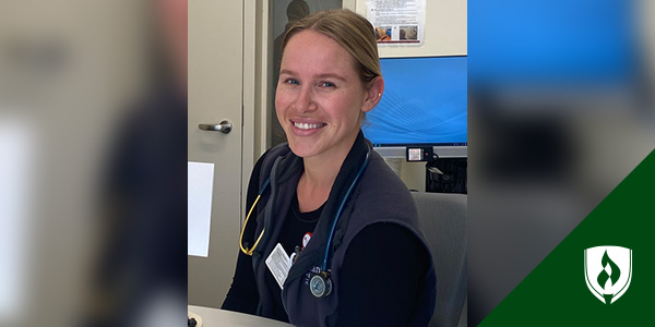 smiling female trauma nurse sitting at table with stethoscope around neck