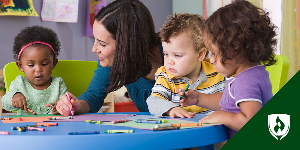 Photo of an adult interacting with preschoolers who are coloring and asking questions.