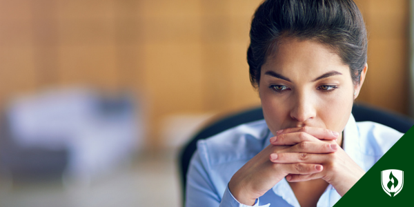 An accountant stares pensively at her desk, deep in thought