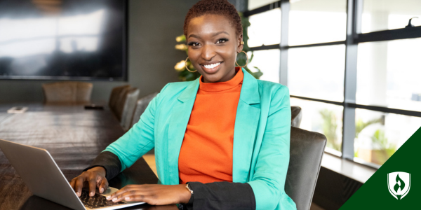 A business student in a turquoise blazer sits in a conference room