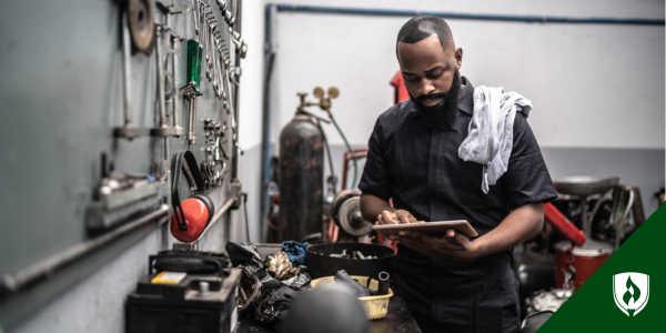 A small business owner in a tool shop looks at his tablet