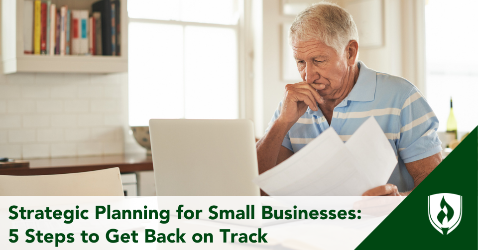 A small business owner stares into his computer with papers in hand