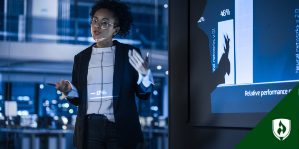 A business professional in glasses gives a presentation, gesturing with her hands