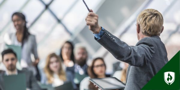 A speaker gestures emphatically in front of a gathering of professionals