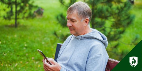 Someone sits on a park bench while shopping online