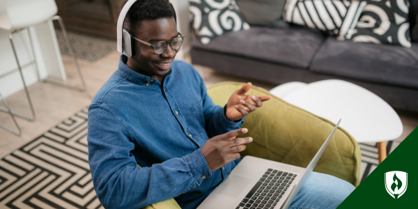 An ECE student smiles and talks into his computer and headphones