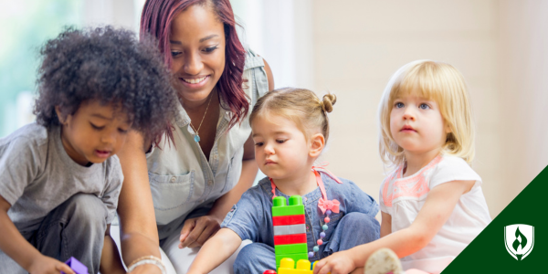 An early childhood teacher assists three young kids with their blocks