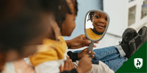 Adorable toddler smiles at his reflection in a mirror