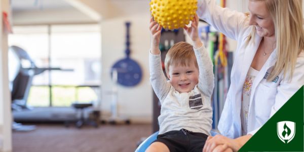 A pediatric PTA works with a young child and a yellow ball