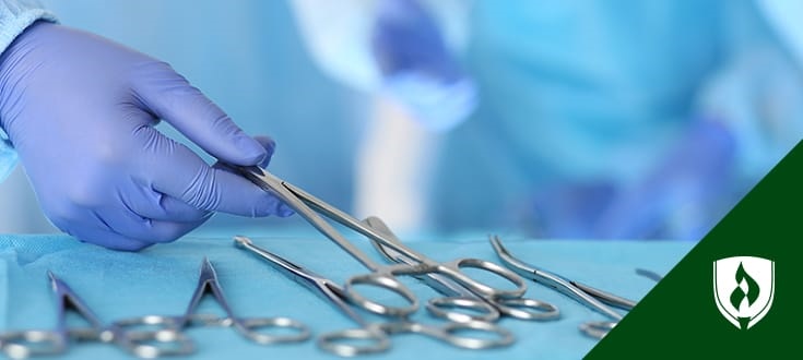 hand in a medical glove grabbing a surgical scissors