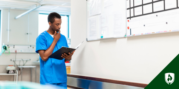 A nurse stands in a healthcare breakroom, looking over some papers