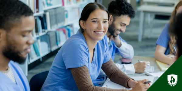 Nurses sit laughing and learning at a table