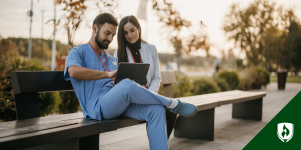 A nurse and nurse practitioner sit on a bench looking at multistate licensure information