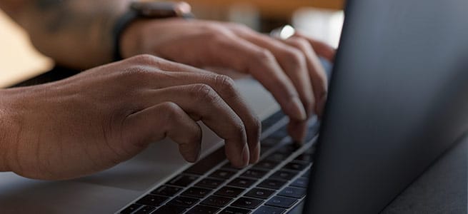 close up of hands typing on a laptop keyboard