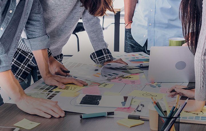 hands on a desk with sticky notes and papers