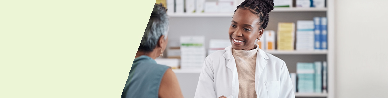 A pharmacy technician smiling at a patient in a pharmacy setting