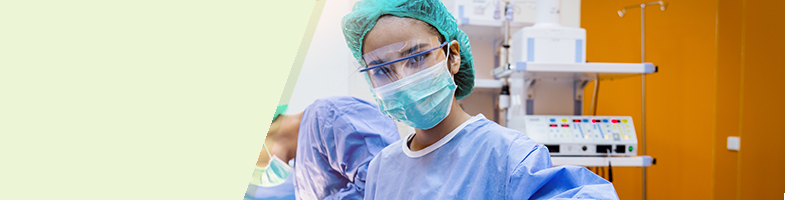 Surgical technologist in full PPE looking at camera