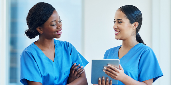 two nurses smiling over tablet