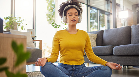 woman wearing headphones with eyes closed sitting in yoga pose