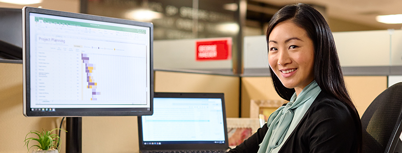 female information technology manager sitting in front of screens