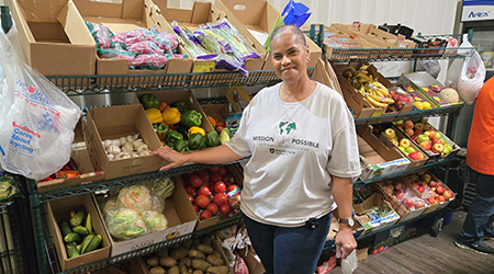 Rasmussen University employee standing in front of food boxes at a volunteer event